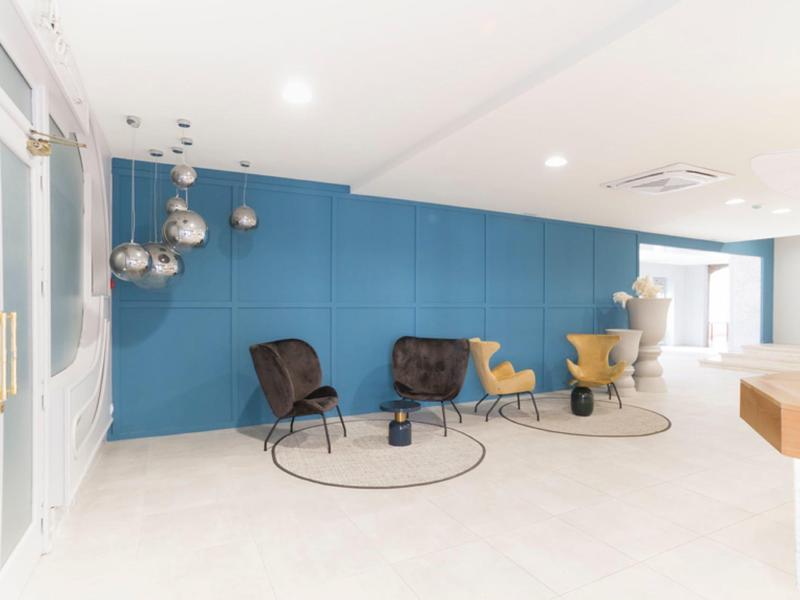 Sala de espera moderna con sillas de diseño y pared azul en un espacio limpio y luminoso.