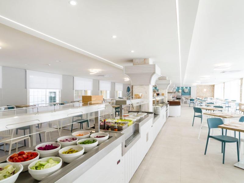 Sala moderna y luminosa del hotel con estación de buffet y áreas para sentarse en blanco y azul.