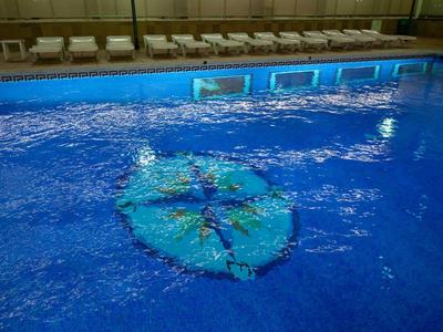 Blauer Hallenbadpool mit einem großen, grünen Tennisschläger, der unter Wasser liegt.