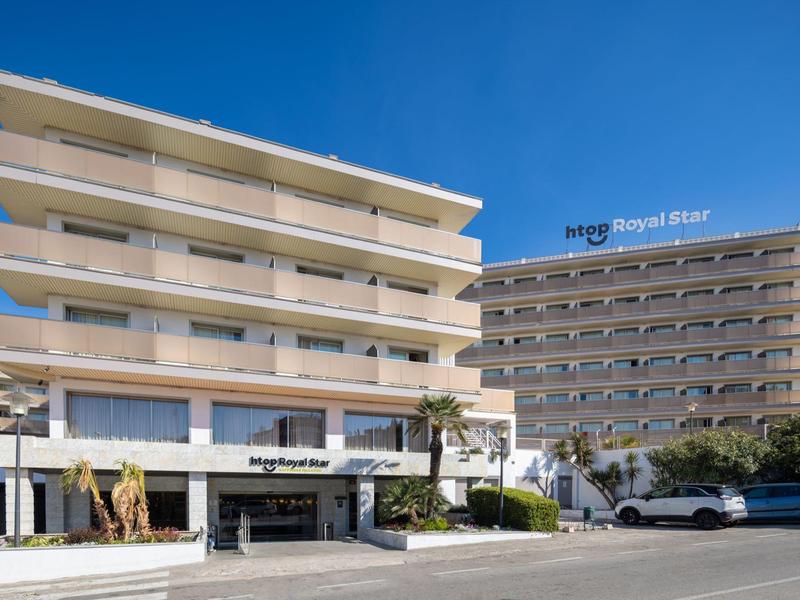 Moderno edificio alberghiero con balconi e insegna HRC Royal Resort visibile sotto un cielo limpido.