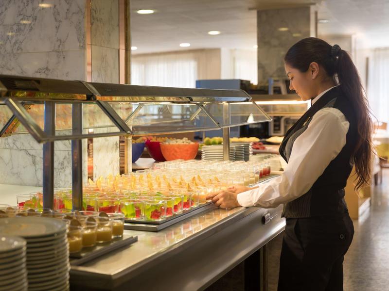 Una cameriera sistema dessert colorati al buffet dell'hotel.
