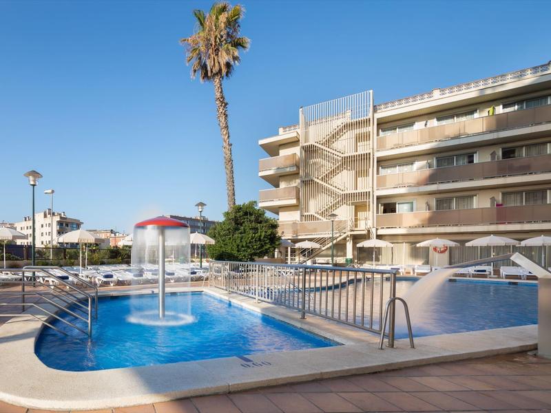 Piscina per bambini con gioco d'acqua e grande edificio dell'hotel sullo sfondo in una giornata di sole