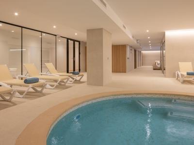 Moderner Wellnessbereich mit Whirlpool und Liegestühlen in neutralen Farben.
