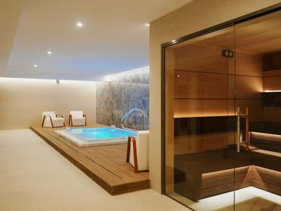 Moderner Wellnessbereich mit Whirlpool und Holzsauna in einem Hotel.