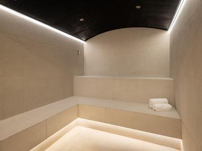 Moderner Spa-Ruheraum mit hellen Steinbänken und gedämpfter Beleuchtung.