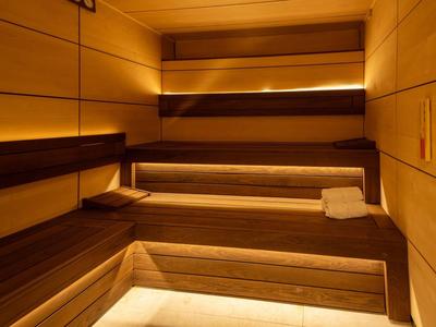 Moderne Sauna mit Holzvertäfelung, warmem Licht und Handtüchern auf der Bank.