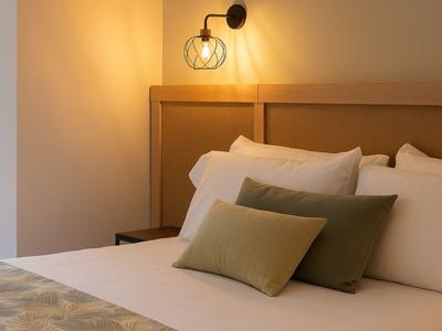 Ein gemütliches Hotelzimmer mit weichen Kissen und warmem Licht an der Wand.