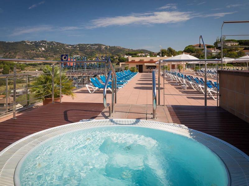 Vírivka na terase s lehátky a výhledem na kopce a oblohu.