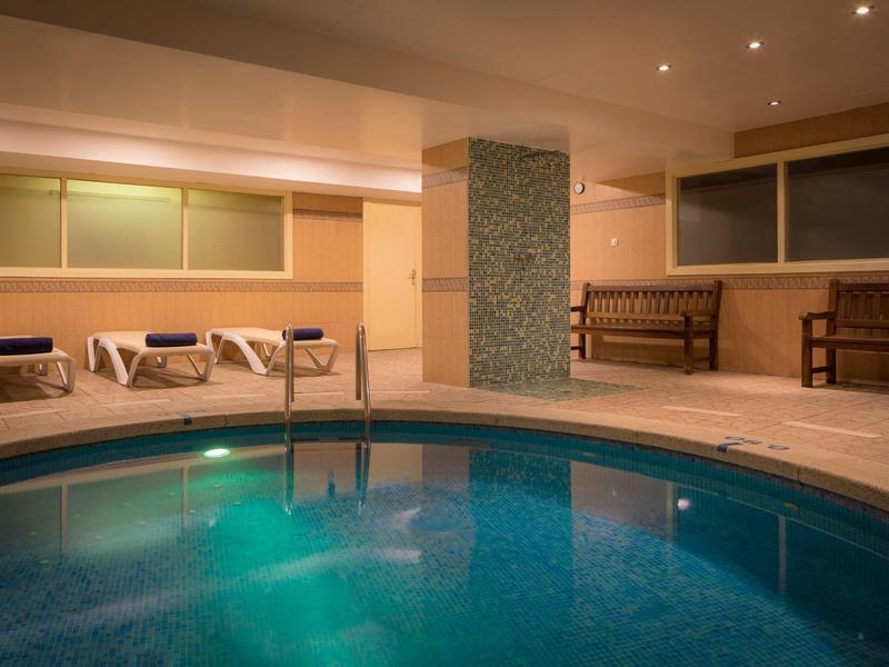 Vytápěný krytý bazén s dvěma lavicemi a tlumeným osvětlením v teplých tónech.