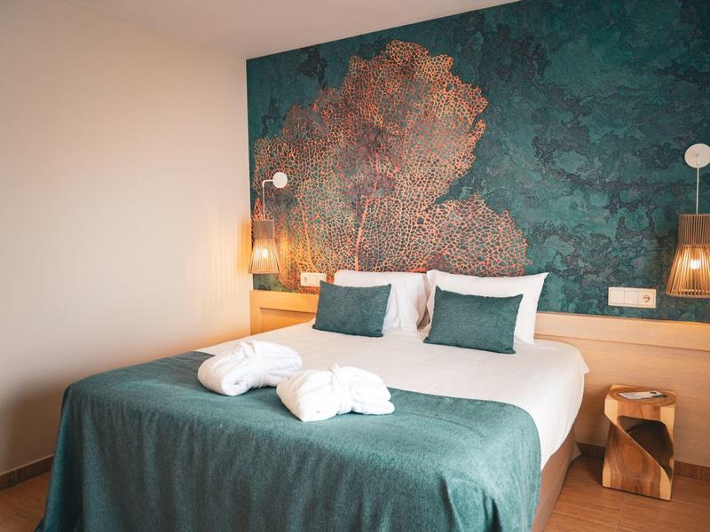 Gemütliches Schlafzimmer mit großem Bett und Waldwandbild im modernen Hotel.