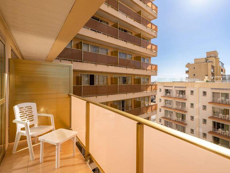 Balkon mit Plastikstuhl und Tisch in einem mehrstöckigen Gebäude bei sonnigem Wetter.