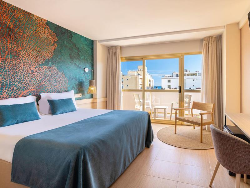 Modernes Hotelzimmer mit Doppelbett, Sitzbereich und Balkon mit Stadtblick.