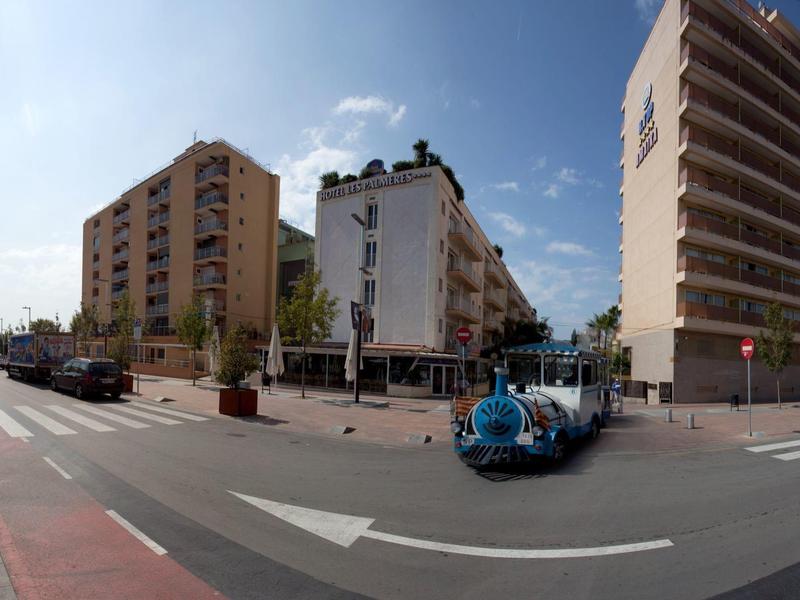 Breite Straßenansicht mit großen Apartmentgebäuden und einem kleinen blauen Touristenboot.
