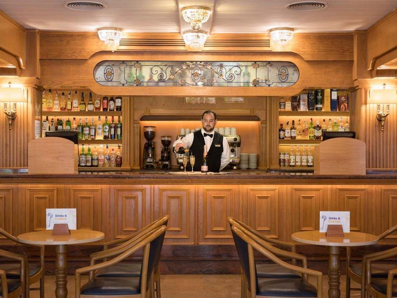Gemütliche Hotelbar mit Holztheke und Barkeeper in klassischem Ambiente.