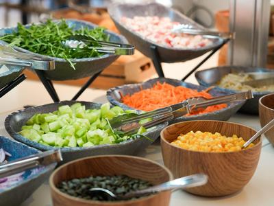 Vari ingredienti freschi per insalata in ciotole su un buffet.