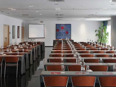 Sala conferenze con file di tavoli, sedie e acqua per riunione