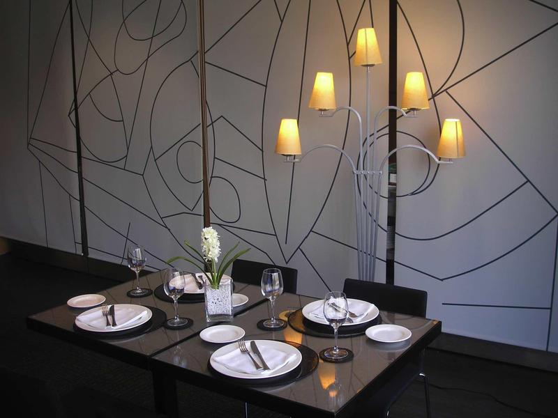 Tavolo da pranzo elegante apparecchiato con piatti e lampada da parete moderna in ambiente raffinato.