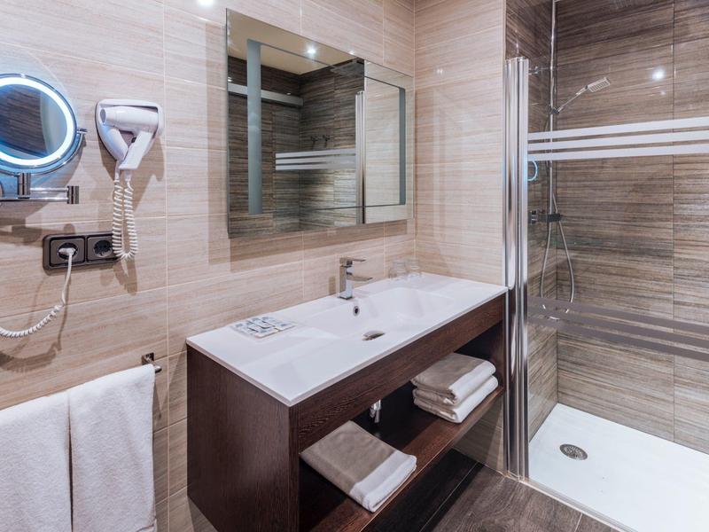 Moderne badkamer met wastafel, spiegel, föhn en douche.