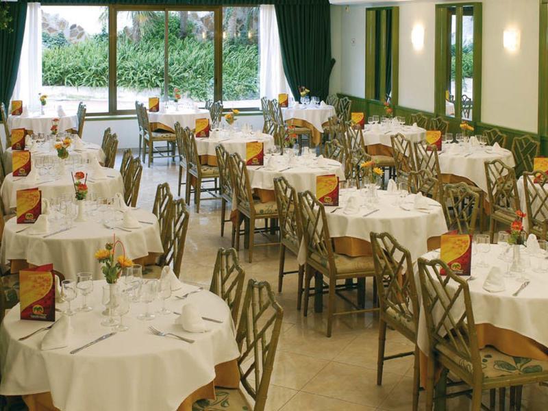 Elegant restaurant met gedekte tafels en uitzicht op een groene tuin door grote ramen.