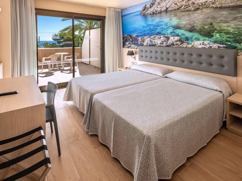 Hotelkamer met twee eenpersoonsbedden, bureau, balkon en zeezicht