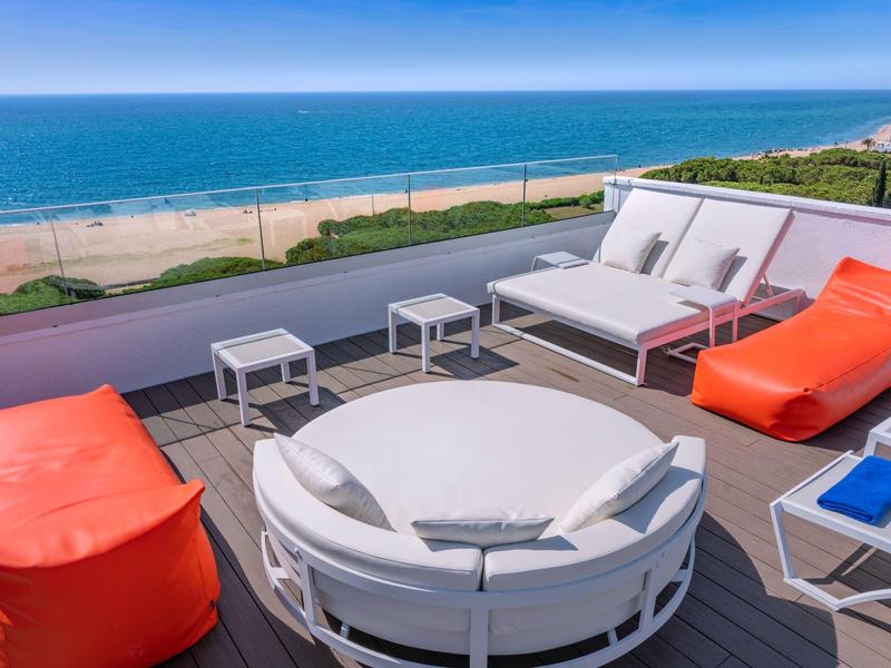 Moderne terras met comfortabele zitplaatsen en uitzicht op het strand en de zee.