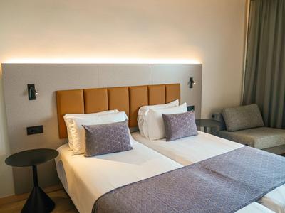 Moderne hotelkamer met twee eenpersoonsbedden, nachtkastje en gezellige zithoek.