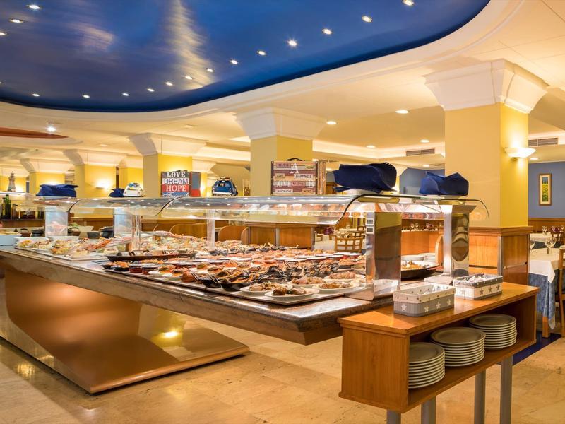 Buffet elegante de hotel con luz cálida y variedad de platos sobre una mesa larga.