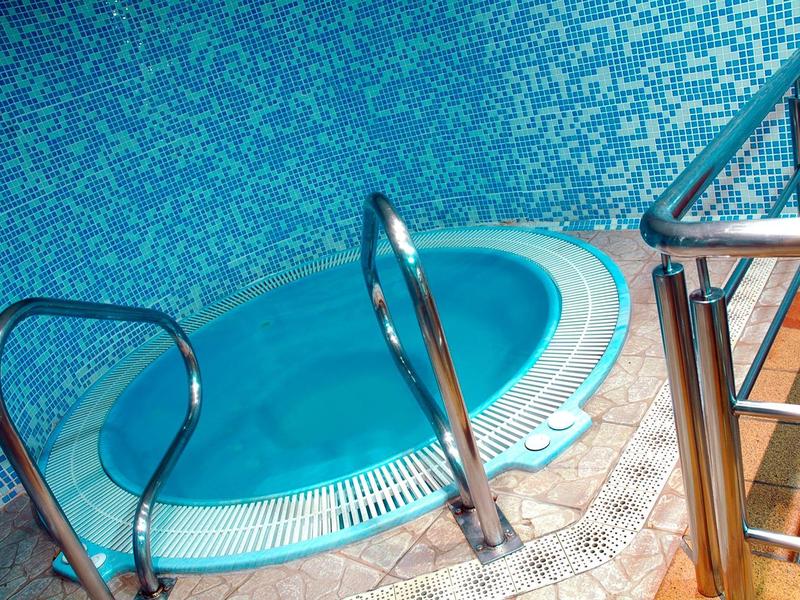 Piscina interior azul con barandilla metálica y bordes de azulejos.