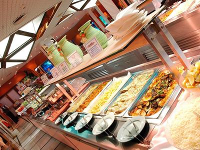 Buffet mit warmem Essen, Tellern, Besteck und Getränken in einem Restaurant.