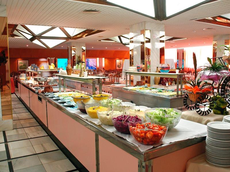 Buffet mit vielfältigen frischen Salaten und kalten Speisen in hellem Restaurant mit Pflanzen.