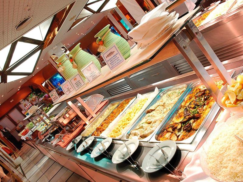 Buffet mit warmem Essen, Tellern, Besteck und Getränken in einem Restaurant.