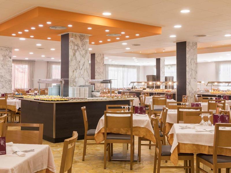 Amplio comedor en un hotel con mesas y sillas de madera, y decoración moderna.