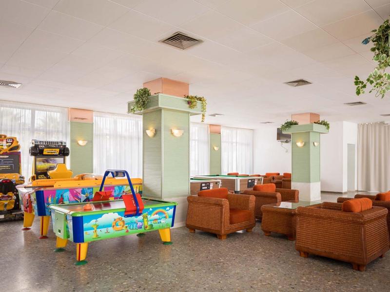 Sala común grande con mesas de juegos y sillones de cuero, luminosa y acogedora.