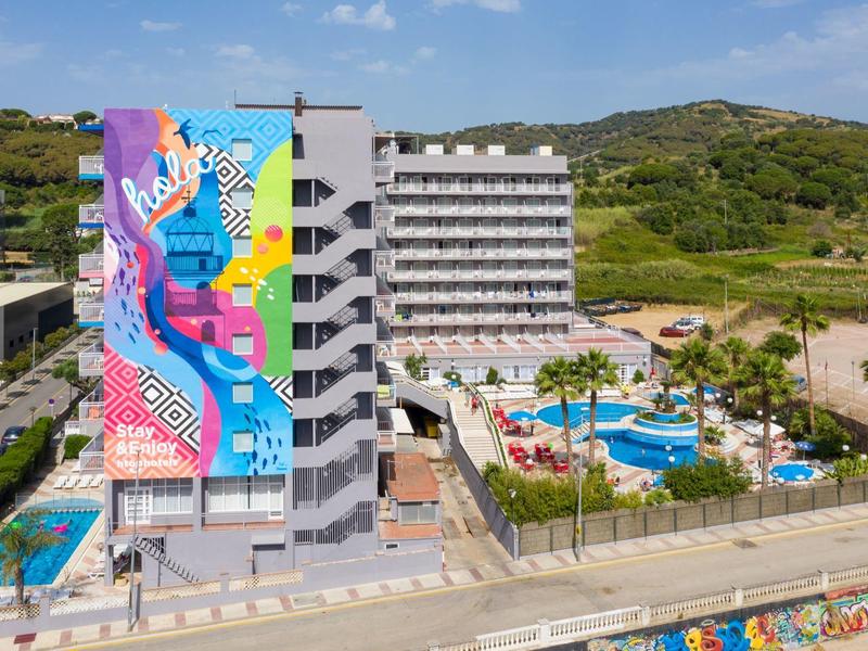 Hotel moderno con gran mural colorido y piscina al aire libre en un paisaje verde.
