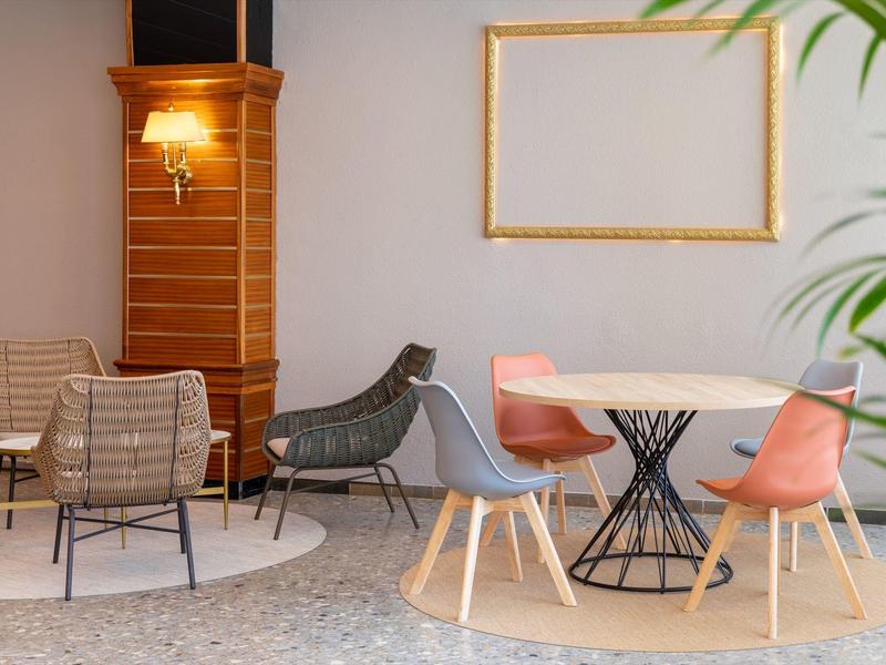 Área de salón moderna en hotel con sillas y mesas coloridas en ambiente relajado.