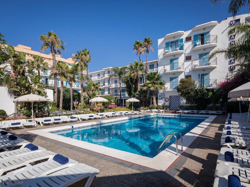 Piscina del hotel con tumbonas y palmeras en zona exterior soleada de un resort.