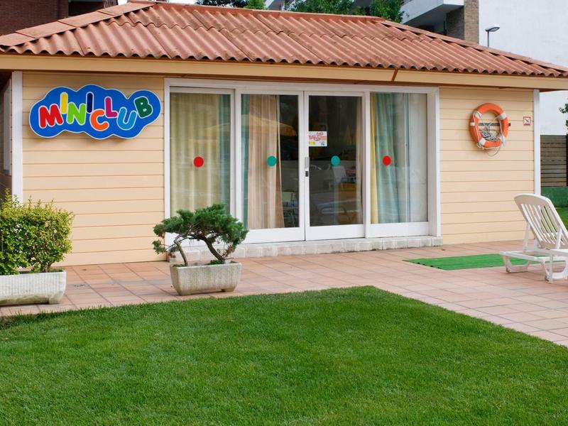 Pequeña casa de juegos en un hotel con césped y muebles de exterior junto a la piscina.