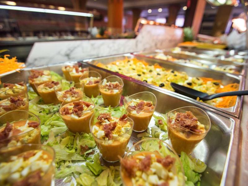 Varie antipasti in piccoli bicchieri su un buffet con un letto di lattuga.