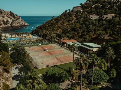 Tennisplätze mit Blick auf das Meer und umgeben von Hügeln und Vegetation.