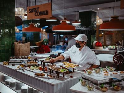 Chef arranging desserts at the buffet in a stylish restaurant or hotel.