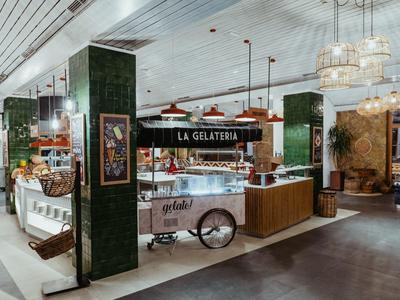Modern gelato shop with cart, wooden counter, and chandeliers in a hotel restaurant.