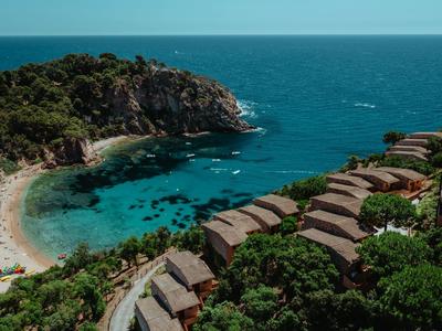 Beach with clear water, rocks, and surrounding bungalows by the sea