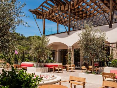 Cozy outdoor terrace with seating and wooden structure, surrounded by trees and plants.