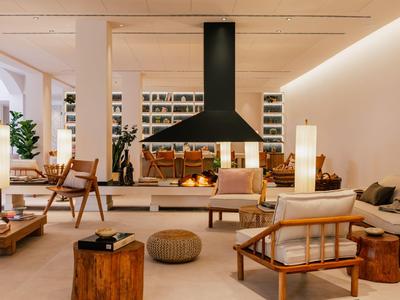 Modernes Wohnzimmer im Hotel mit Kamin, Holz- und Naturmaterialien und bequemen Sitzgelegenheiten.