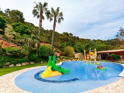 Children's pool with colorful animal figures and palm trees in idyllic garden hotel