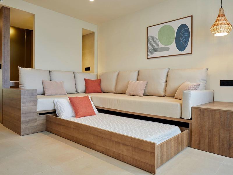 Bright living room with pull-out sofa, modern wood paneling, and decorative wall art.