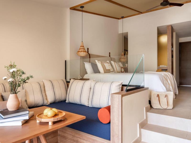 Modern hotel room with double bed, sofa, desk, and cozy decor.