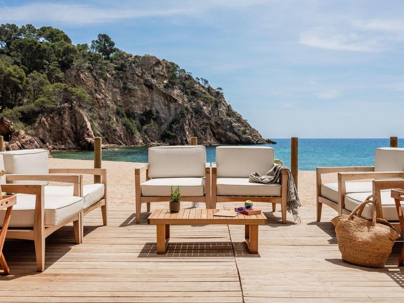 Open terrace with comfortable wooden seating overlooking the beach and sea.