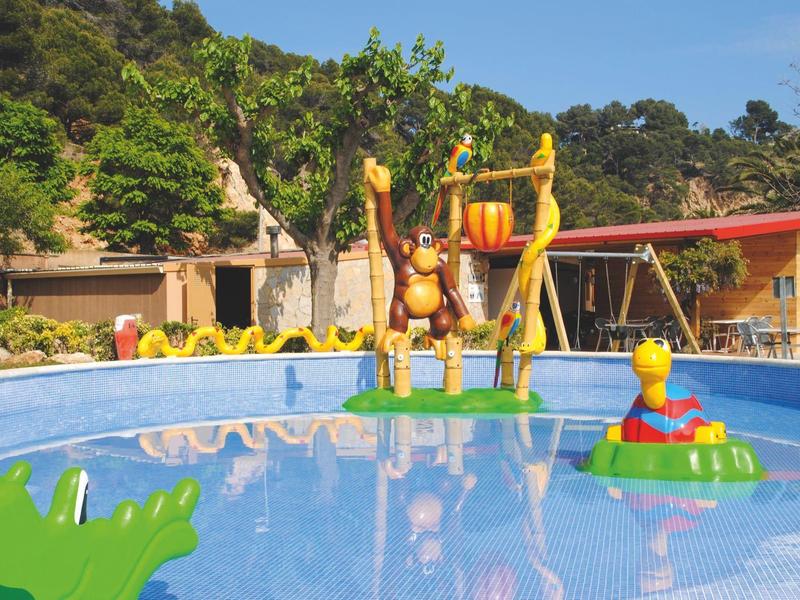 Colorful paddling pool with animal figures and green surroundings in hotel garden.