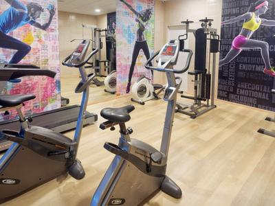 Moderne sportschool met fitnessapparatuur, versierd met sportmuurschilderingen en houten vloer.